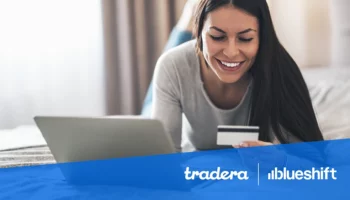 Tradera and Blueshift logos over an image of a woman on a laptop who's smiling and looking at a credit card