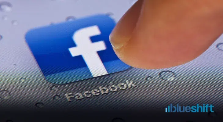 A finger touching the Facebook app icon