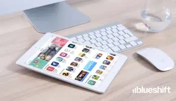 A phone with the app store displayed sitting on a keyboard next to a mouse and a glass of water