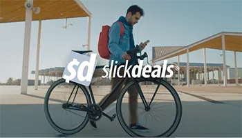 Picture of man in a blue jacket, with a red backpack, checking his phone while walking his bike in an urban area with the slick deals logo overlaying the image.