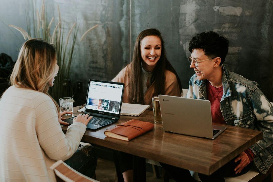 Three professionals collaborating around laptops in a modern workspace, representing customer engagement strategies in action