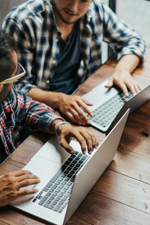 two men working together on laptops